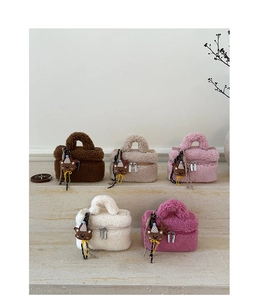 Detail of colorful plush mini handbags with cute bear charms on marble steps