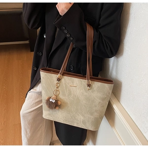 Detail of large beige tote bag with marble texture and brown trim worn by a model