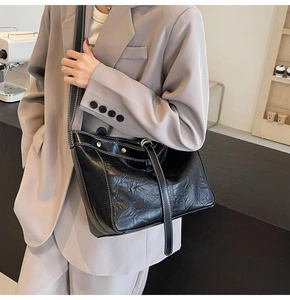 Detail of vintage black pleated crossbody bag with white contrast stitching and rivets