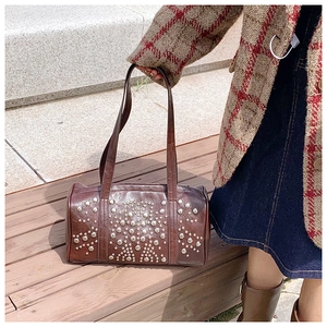 Detail of dark brown leather Boston bag featuring radial silver stud embellishments