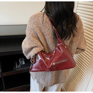 Détail d'un sac à bandoulière en cuir brillant rouge foncé avec fermeture et nœud