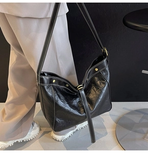 Close-up of black PU leather tote featuring contrast white stitching and gold studs