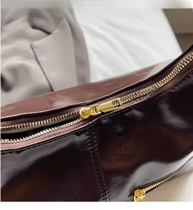 Détail de la fermeture éclair en métal doré sur le sac en cuir marron foncé