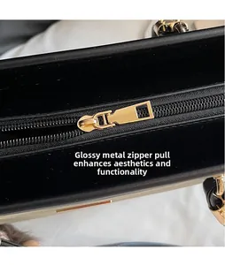 Detail of smooth golden metal zipper and black leather texture on tote bag