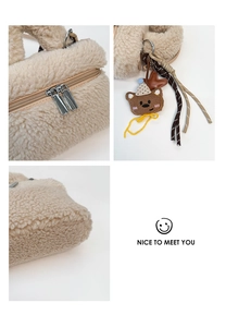 Detail of plush beige mini bag featuring dual metal zippers and cute bear charm pendant