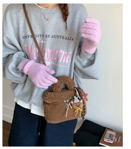 Detail of a plush brown square bag with a teddy bear charm and leather strap