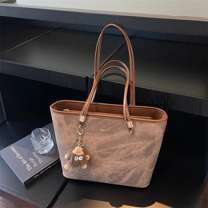 Close-up of retro textured tote bag featuring a slim handle and cute plush charm detail