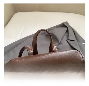 Détail du sac à dos rétro en cuir marron foncé avec doubles poignées et fermoir doré