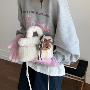 Detailed view of white plush handbag with bear pendant worn with winter hoodie