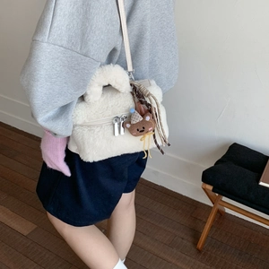 Detail of off-white plush mini bag with lamb-like fur texture and cute bear pendant
