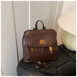 Detail eines dunkelbraunen Vintage-Rucksacks mit goldenem Drehverschluss und Ledertextur