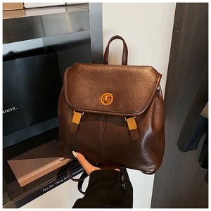 Detail eines dunkelbraunen Vintage-Rucksacks mit Lederstruktur und goldenem Drehverschluss