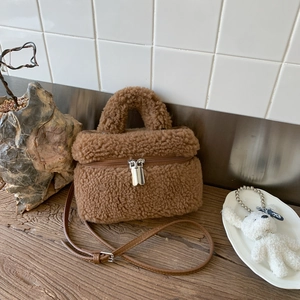 Detail of a brown plush crossbody bag with teddy fleece texture and metallic zippers