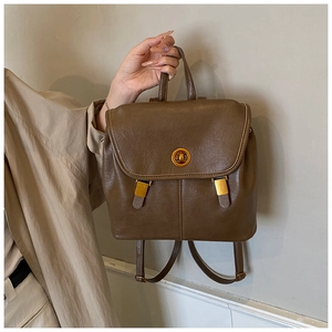 Seitenansicht des braunen Retro-Rucksacks mit goldenem Drehverschluss und feiner Lederstruktur