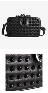 Macro detail of black studded square bag featuring punk rivets and metallic clasp closure