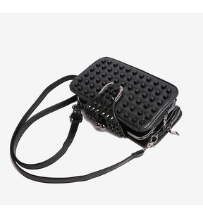 Detail of black crossbody bag featuring silver horseshoe buckle and studded flap cover