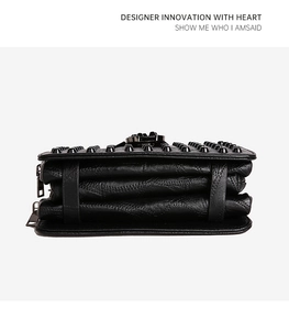 Detail of black pebbled leather handbag with studded rivets and triple-layer accordion design