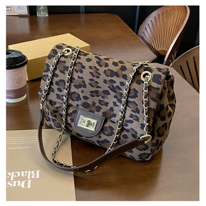 Leopard print crossbody bag with gold chain strap and metal lock on a wooden desk