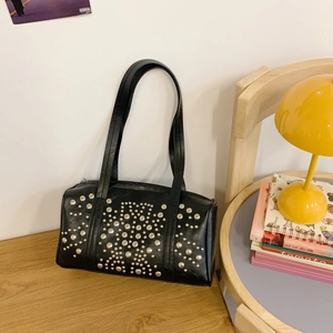 Chic black PU underarm bag with silver studs and long shoulder strap on wooden table