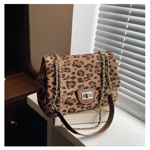 Detail of leopard print crossbody bag with gold turn-lock closure on vintage books