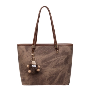 Large brown vintage tote bag with textured finish and cute plush monster charm
