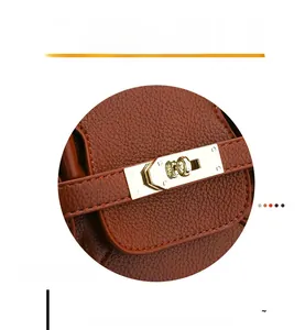 Gros plan du fermoir doré et de la texture du cuir grainé marron sur un sac à main chic