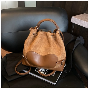 Détail d'un sac seau marron avec cordon de serrage, texture suédée et patch cœur en cuir