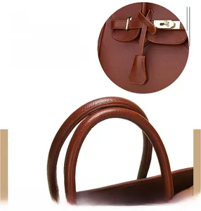 Détail de sac à main en cuir marron foncé avec fermoir doré et surpiqûres