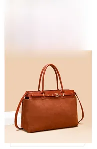 Detail view of brown textured leather tote with metal buckle and suede patchwork design