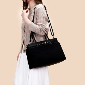 Detail of black large tote bag featuring gold buckle accents and a minimalist design