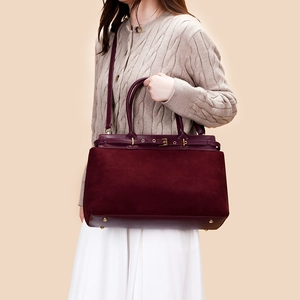 Close-up of burgundy suede tote bag showing gold protective studs and premium leather detail