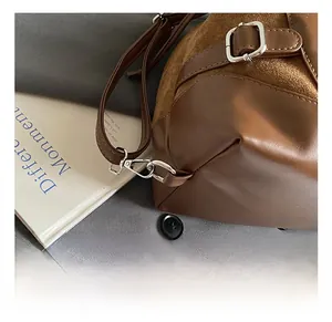 Détail du crochet en métal argenté et du cuir marron texturé d'un sac à bandoulière