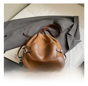 Détail du sac seau marron avec fermeture à cordon et boucle argentée sur cuir suédé