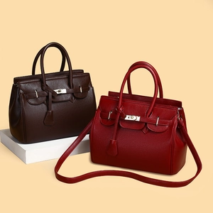 Détail de sacs cabas en cuir grainé marron café et rouge avec fermoir rotatif en métal