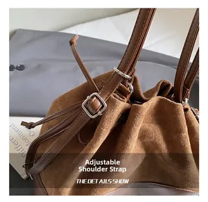 Détail de la boucle argentée réglable et coutures sur le sac seau en daim marron