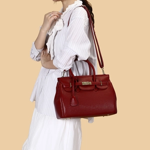 Détail du sac à main en cuir bordeaux avec texture litchi et fermoir doré rotatif
