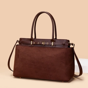 Minimalist dark brown tote bag with vintage stitching and gold buckle on beige background