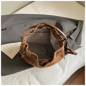 Détail intérieur du sac seau en daim marron avec doublure rayée et fermoir magnétique