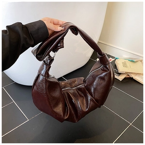 Detail of dark brown pleated crescent bag featuring retro waxed texture and knotted handle