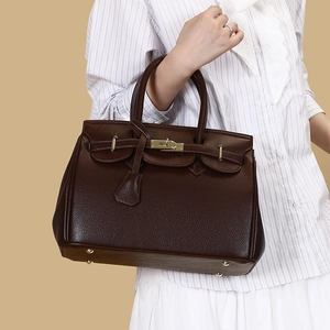 Gros plan détaillé du sac en cuir marron foncé avec texture grainée et cadenas doré