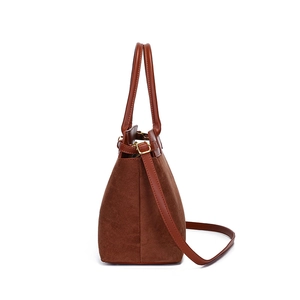 Detailed side view of brown suede tote bag with leather straps and gold metal buckles