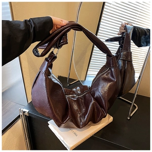 Detail of burgundy patent leather bag with pleated texture and silver zipper closure