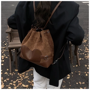 Gros plan du sac seau en daim marron avec empiècement cœur en cuir et cordon de serrage