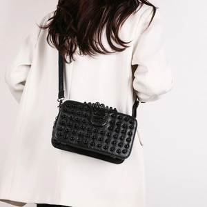 Fashionable black studded rectangular crossbody bag with slim strap on white coat