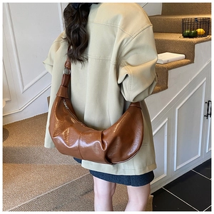 Detail of a brown glossy hobo bag with knotted strap shown in a lifestyle setting