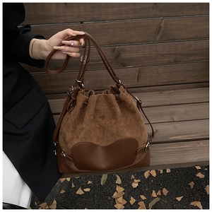 Détail d'un sac seau marron foncé en daim avec fermeture à cordon et boucles argentées