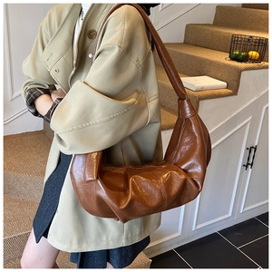 Detail of vintage brown crescent hobo bag with pleated texture and glossy finish