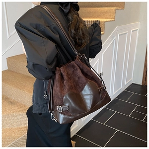 Détail d'un sac seau marron à cordon alliant textures en daim et cuir lisse