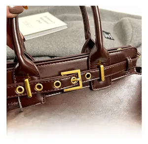 Detail of vintage dark brown leather bag showing premium gold hardware and belt buckle strap