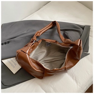 Detail of a brown PU leather hobo bag featuring a unique knotted shoulder strap and silver zipper